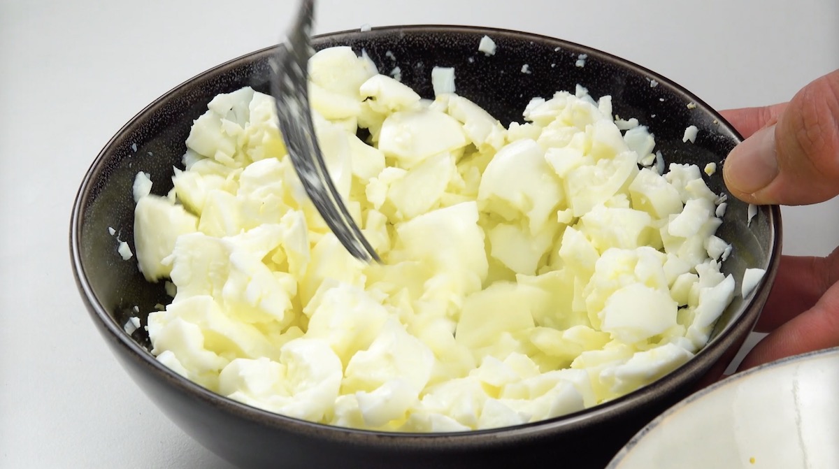 Eigelbe in einer Schüssel werden mit Gabel grob zerkleinert