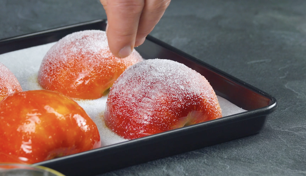 Die eingeschnittenen Apfelhälften werden auf ein Backblech gelegt und mit Zucker bestreut