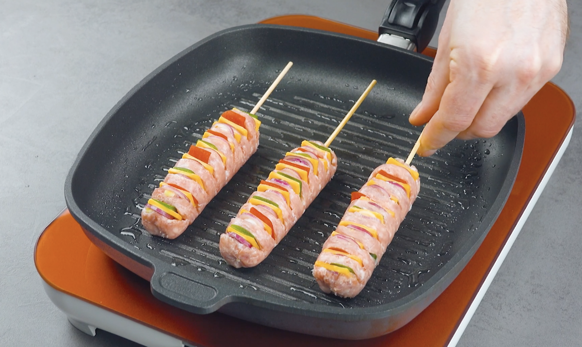 Die Hasselback-Bratwürste erden in Pfanne angebraten