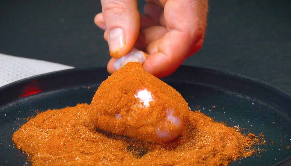 Hähnchenkeule wird in Paprika- und Chilipulver gewälzt