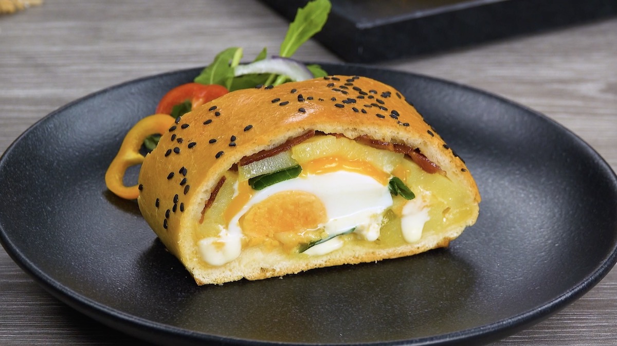 Ein Stück Bauernfrühstück-Calzone auf schwarzem Teller