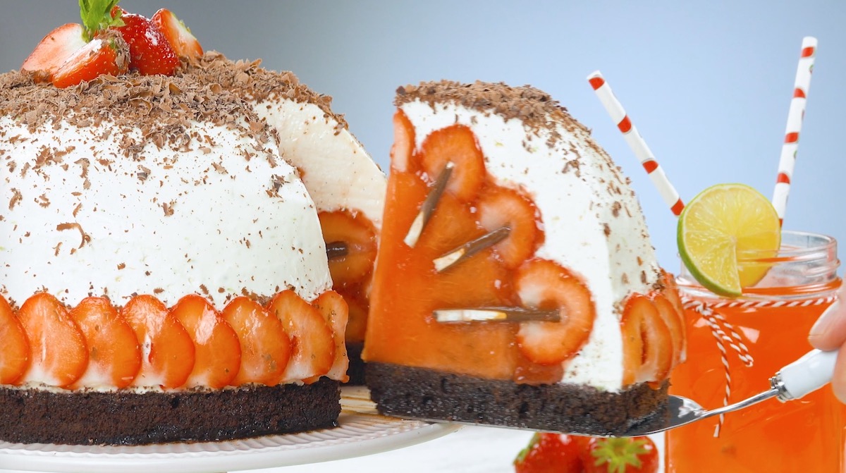 Ein Stück Kuchen mit Melone und Erdbeeren wird aus der Kuppeltorte entnommen