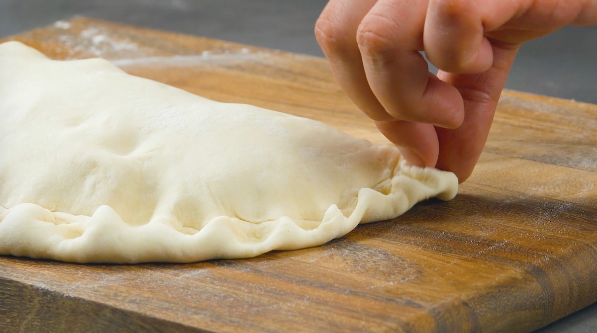 Pizzateig von Calzone wird mit Händen festgedrückt