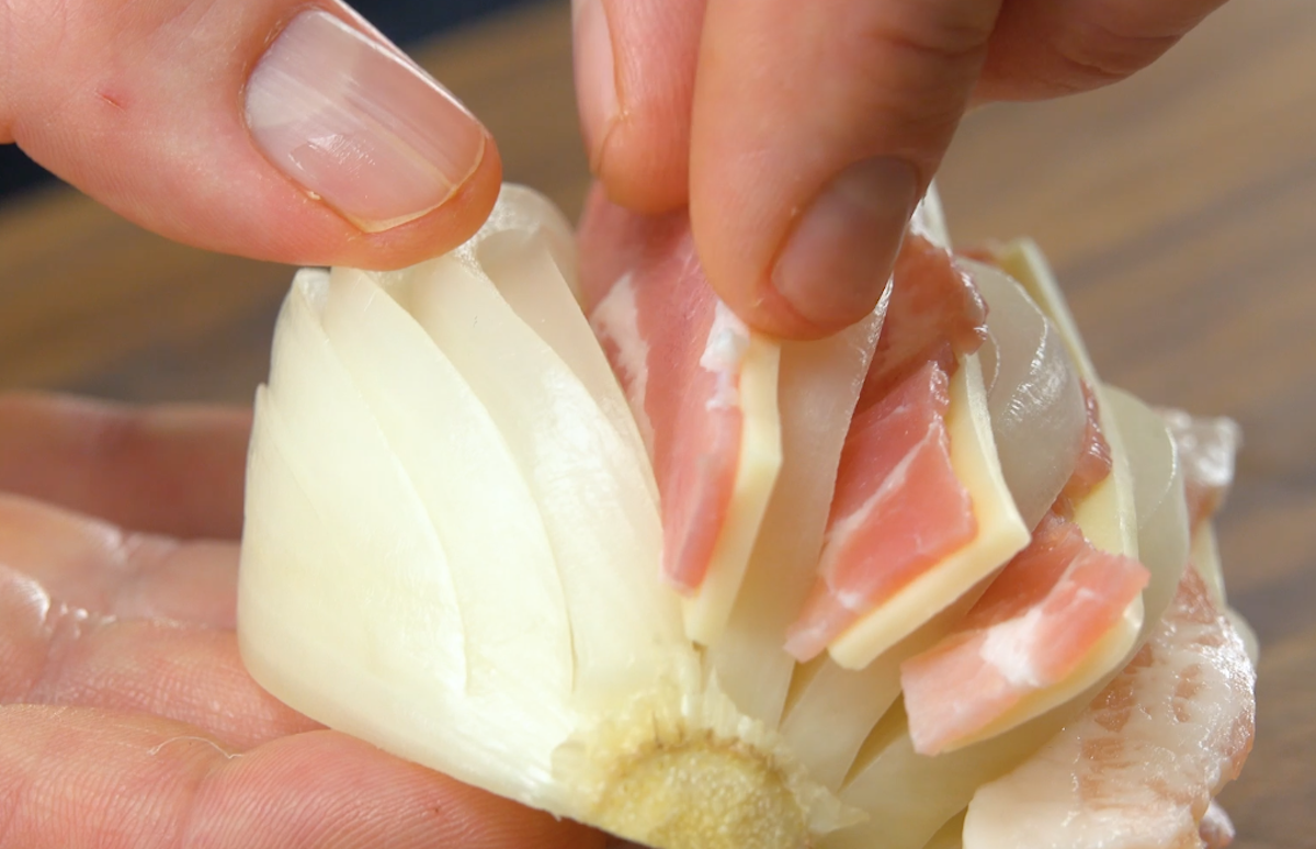 Halbierte und geschälte Zwiebeln werden eingeschnitten und mit Schinken und Käse gefüllt