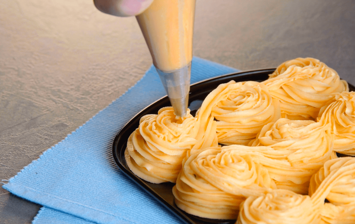 Brandteig wird auf die Rückseite einer Muffinform gespritzt