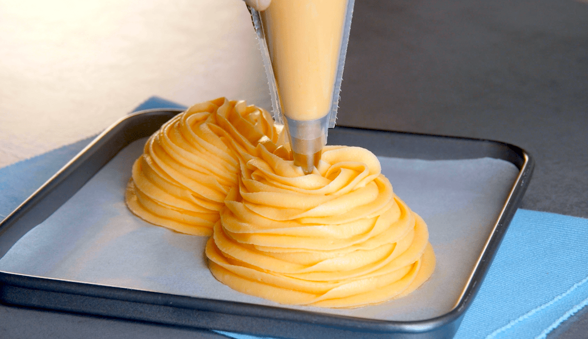 Brandteig wird auf der Unterseite von zwei Schüsseln verteilt