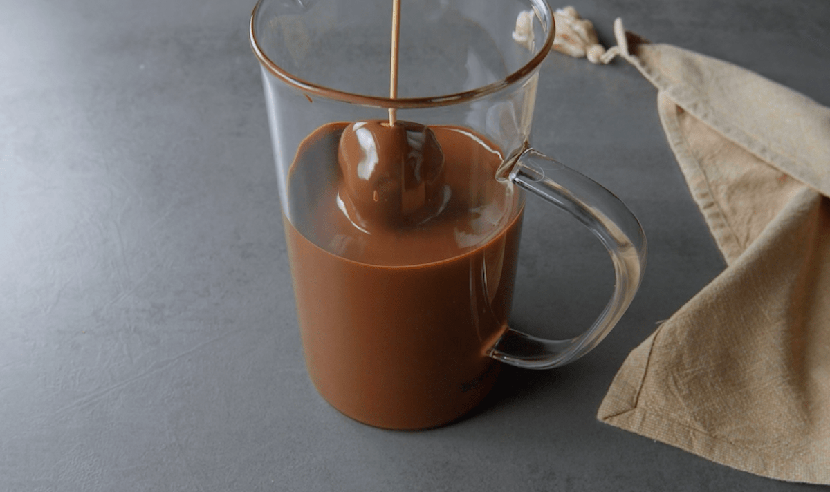 Ein aufgespießter Windbeutel wird in geschmolzene Schokolade getunkt