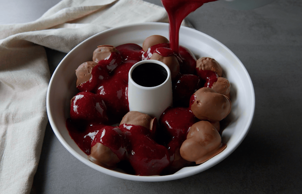 Beerensoße wird über Schoko-Windbeutel gegossen