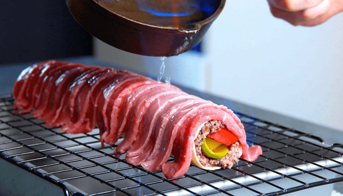 Eine gefüllte Tortillarolle wird mit Rumpsteak belegt und mit Tequila übergossen