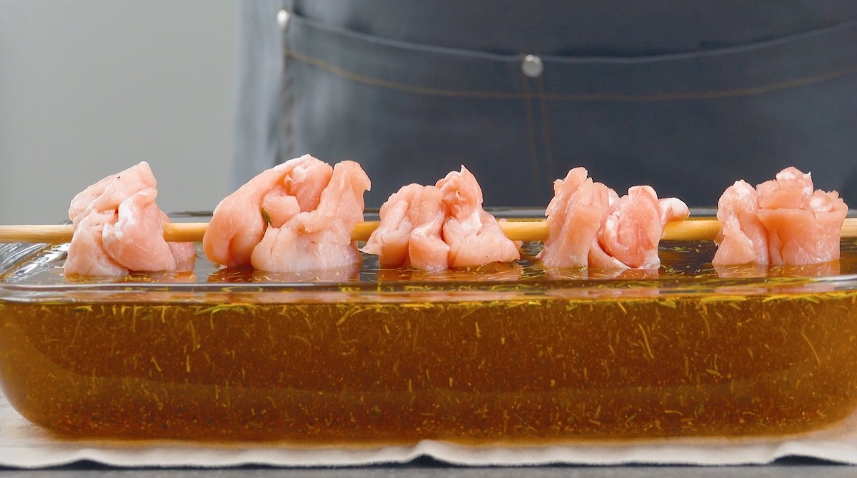 Gefüllte Schweineschnitzel auf Spieß werden in Marinade gehangen