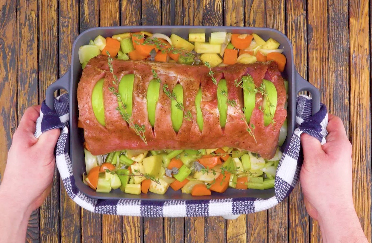 Schweinerücken mit Apfel in einem Bräter.