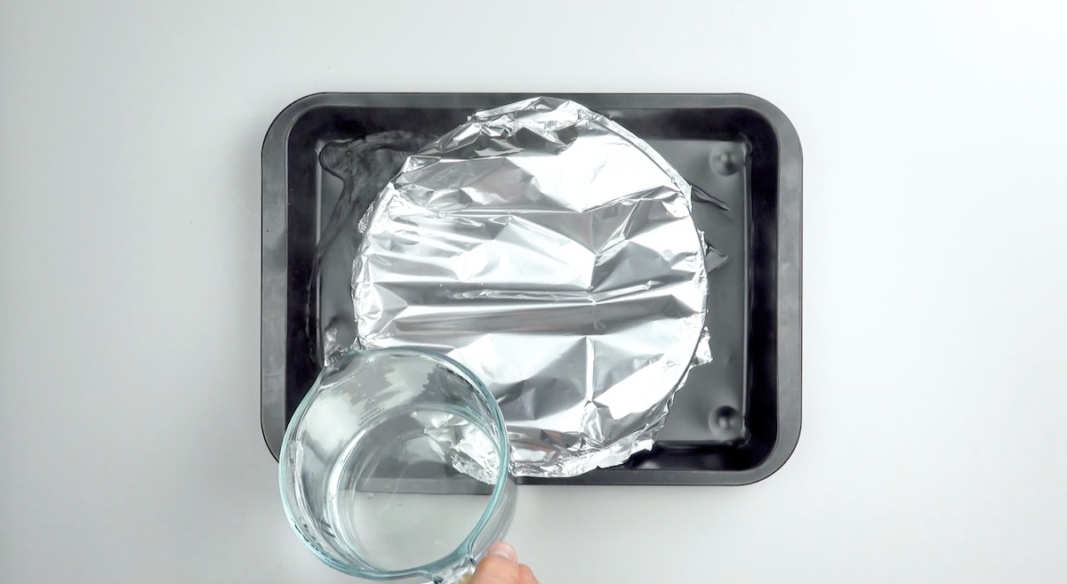 Flan wird auf Backblech gestellt, mit Alufolie abgedeckt und das Blech mit Wasser aufgefüllt