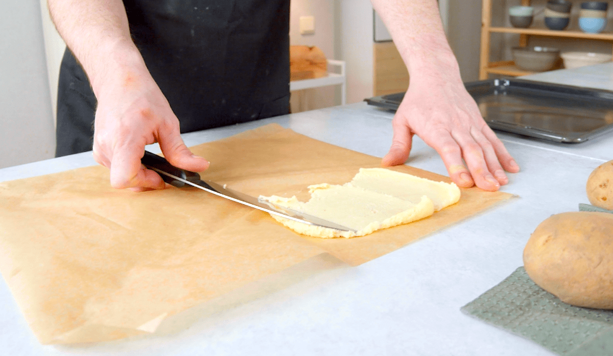Kartoffelbrei wird in einer dünnen Schicht auf Backpapier verteilt.