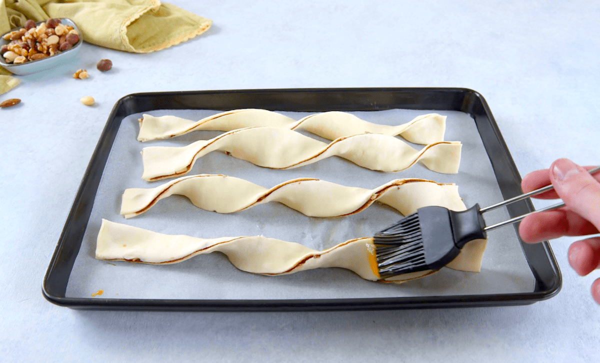 Blätterteigstangen mit Nutella werden mit verquirltem Ei bestrichen.