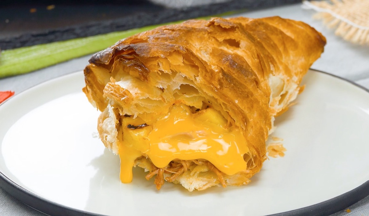 Blätterteigtasche, gefüllt mit Pulled Chicken, Mango und Cheddar, von der abgebissen wurde