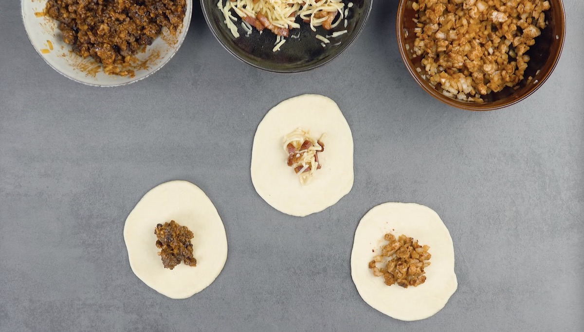 Hefeteige werden ausgerollt und mit verschiedenen Füllungen versehen