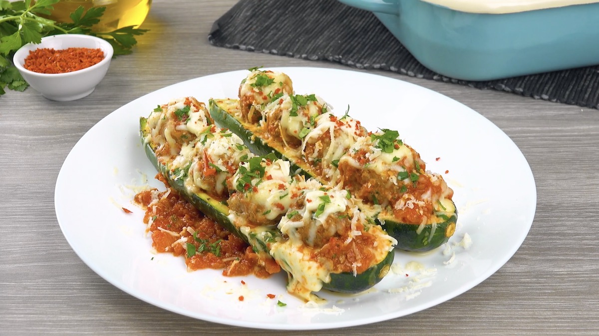 2 mit Hackbällchen gefüllte Zucchini auf Teller
