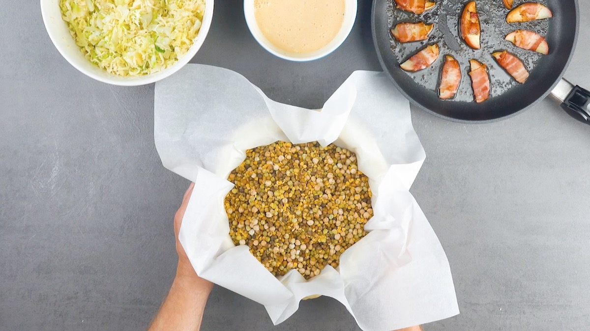 Eine Springform wurde mit Backpapier und Backerbsen gefüllt