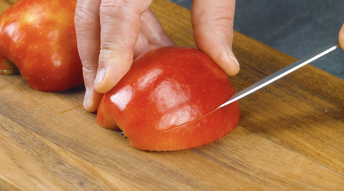 Eine Apfelhälfte wird mit einem Messer längs eingeschnitten