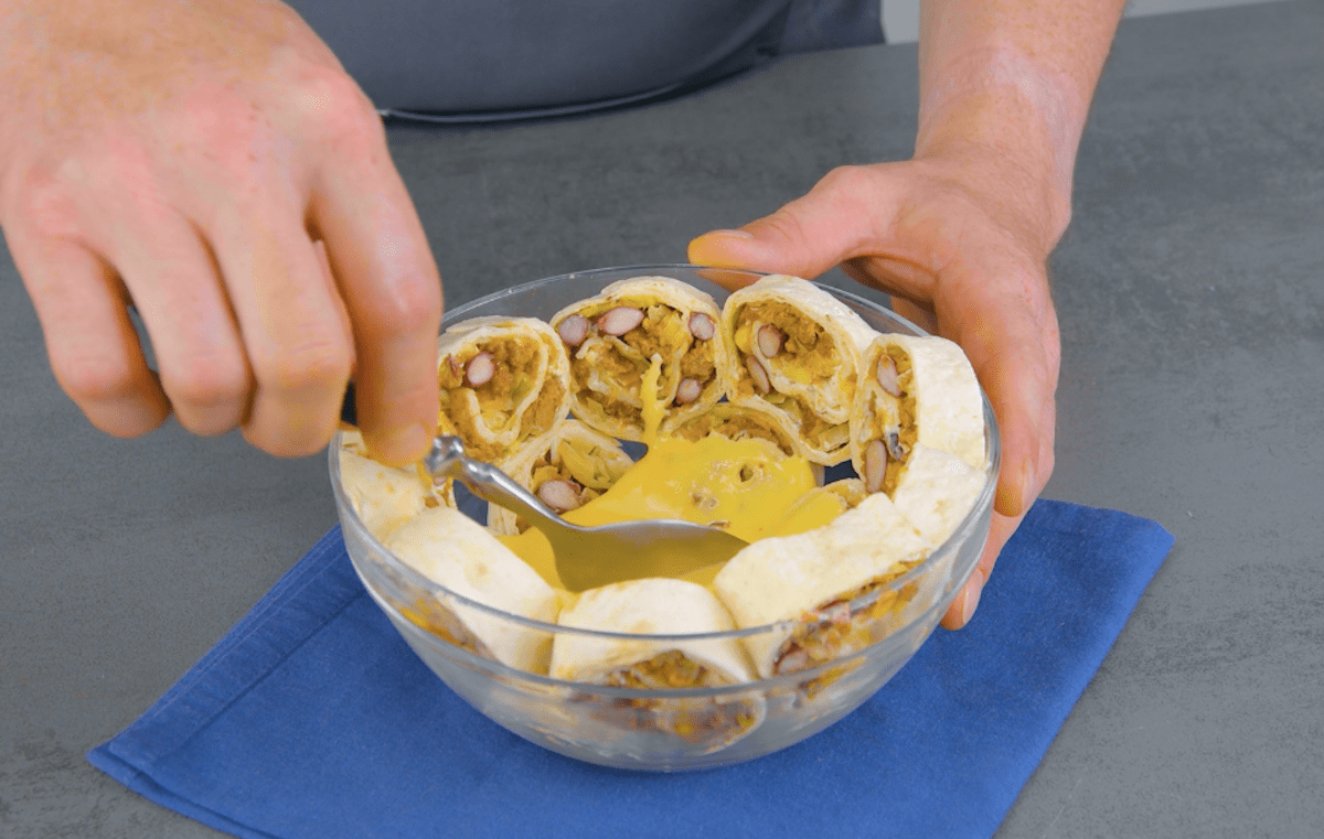 Eine Schüssel wird mit Tortilla Scheiben und Käsesauce gefüllt