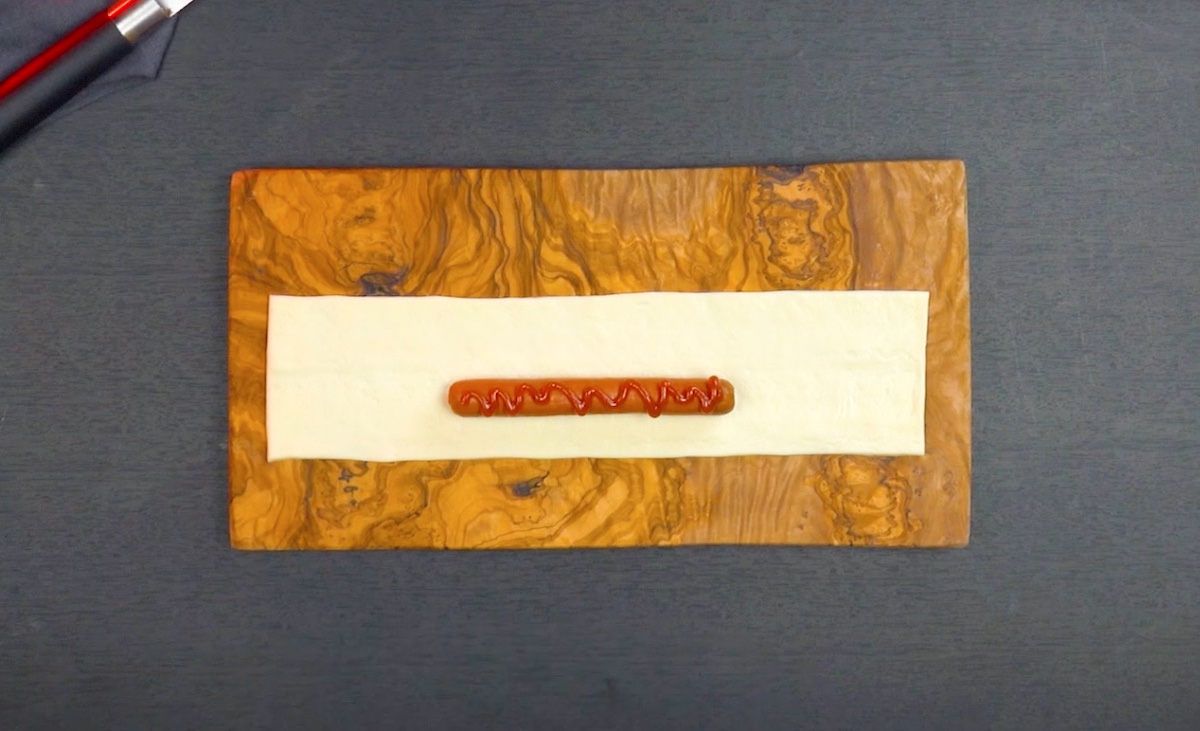 Würstchen wird auf Teig platziert