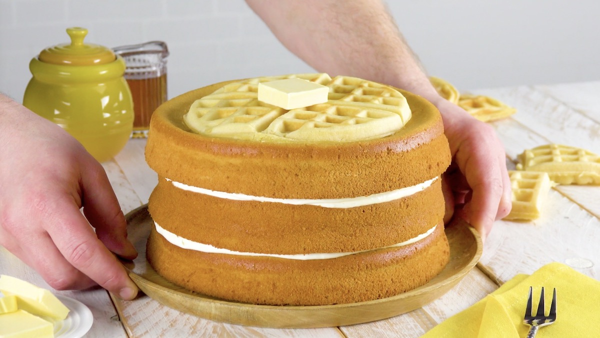 Waffelkuchen mit cremiger Füllung und einem Stück Butter obendrauf wird auf Tisch gestellt