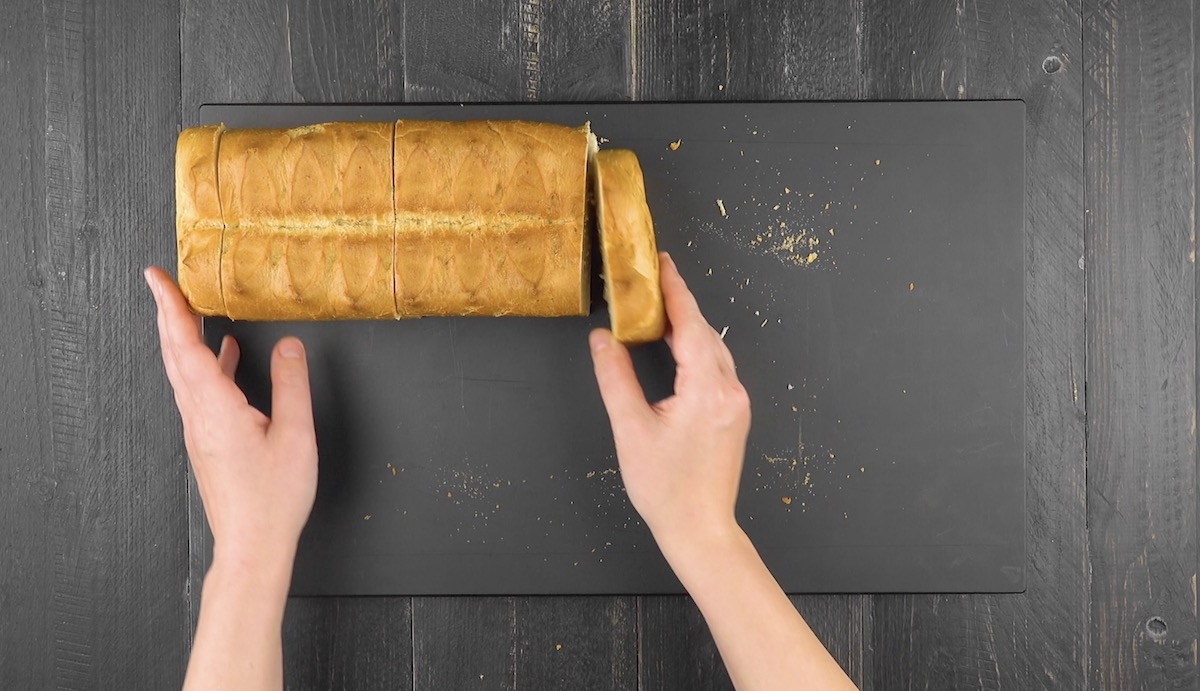 Die Enden eines Weißbrots werden abgeschnitten und das Brot halbiert