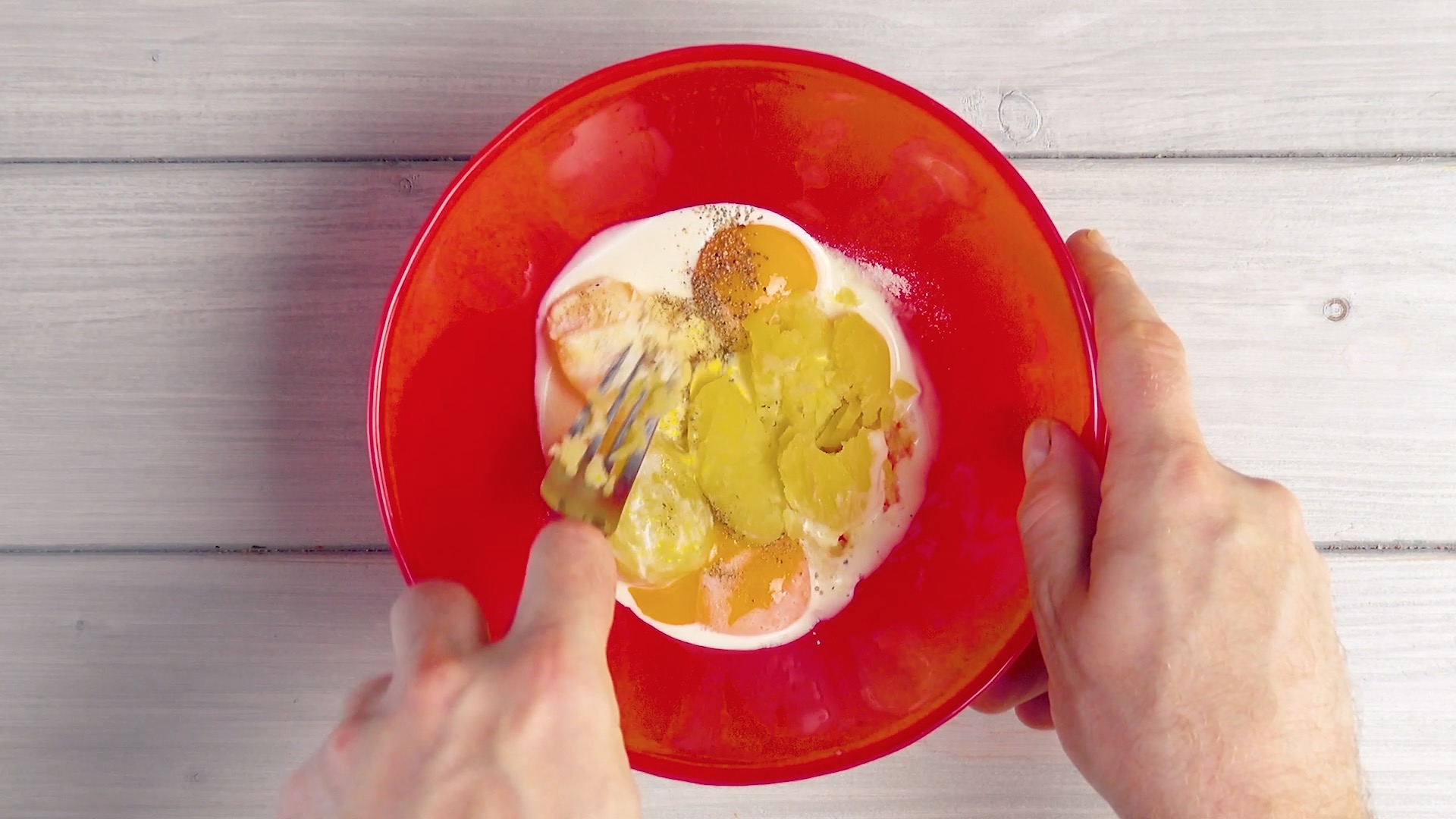 Kartoffeln werden mit Eiern, Sahne und Gewürzen in Schüssel vermengt