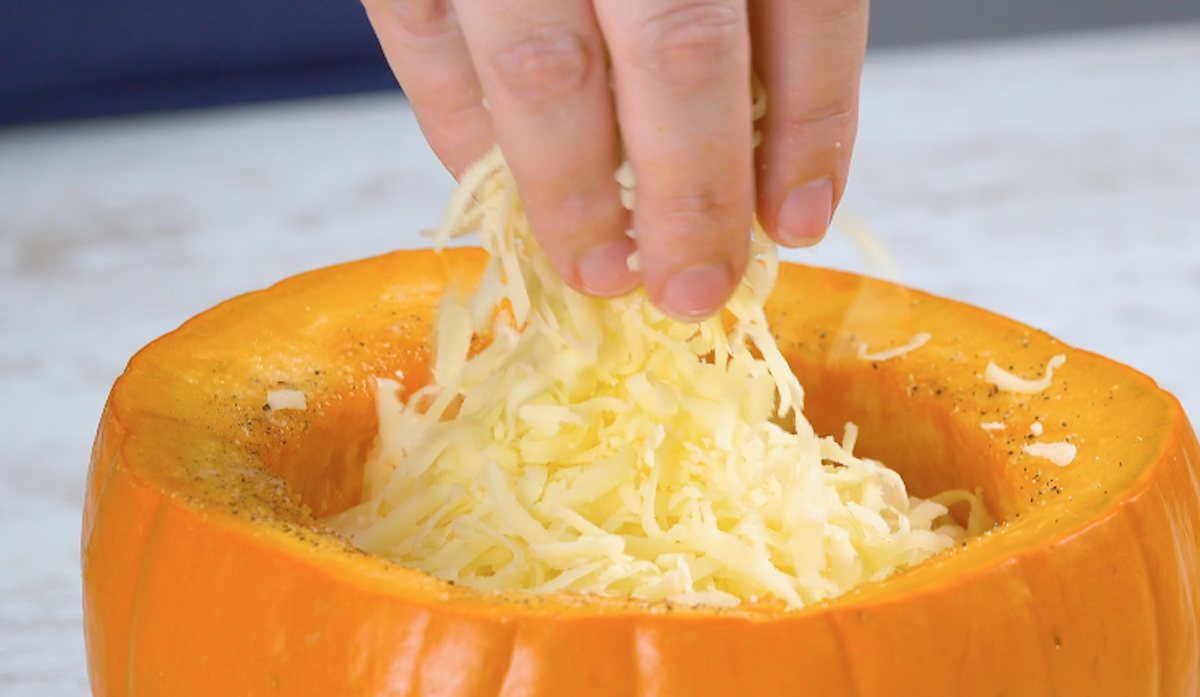Kürbis wird mit geriebenem Käse gefüllt