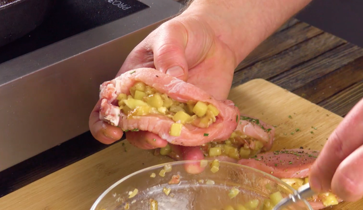 Roher Schweinerücken wird mit Apfelstückchen, Bacon und Zwiebeln gefüllt