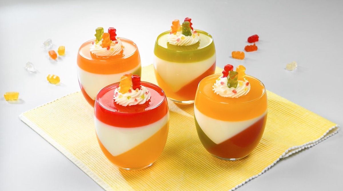 4 Gläser Gummibärchen-Pannacotta auf Platzset aus Stoff mit Sahne und Gummibären als Dekoration