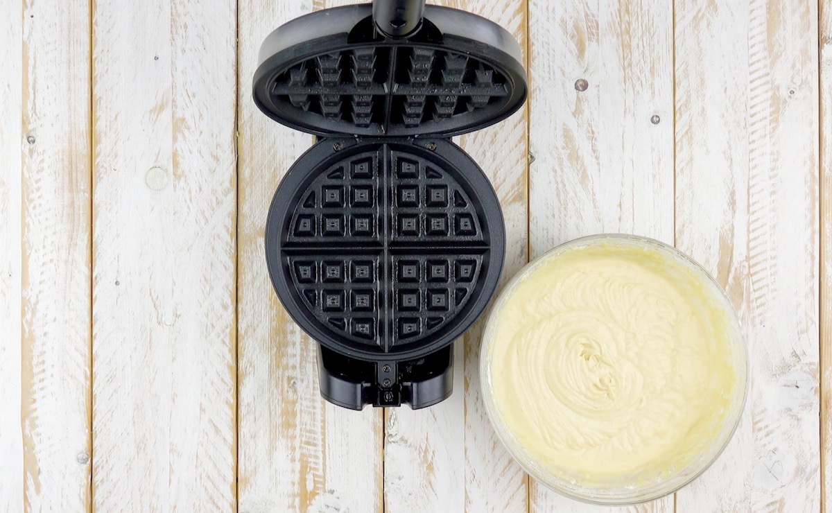 Ein Waffeleisen neben ein Schüssel mit Teig