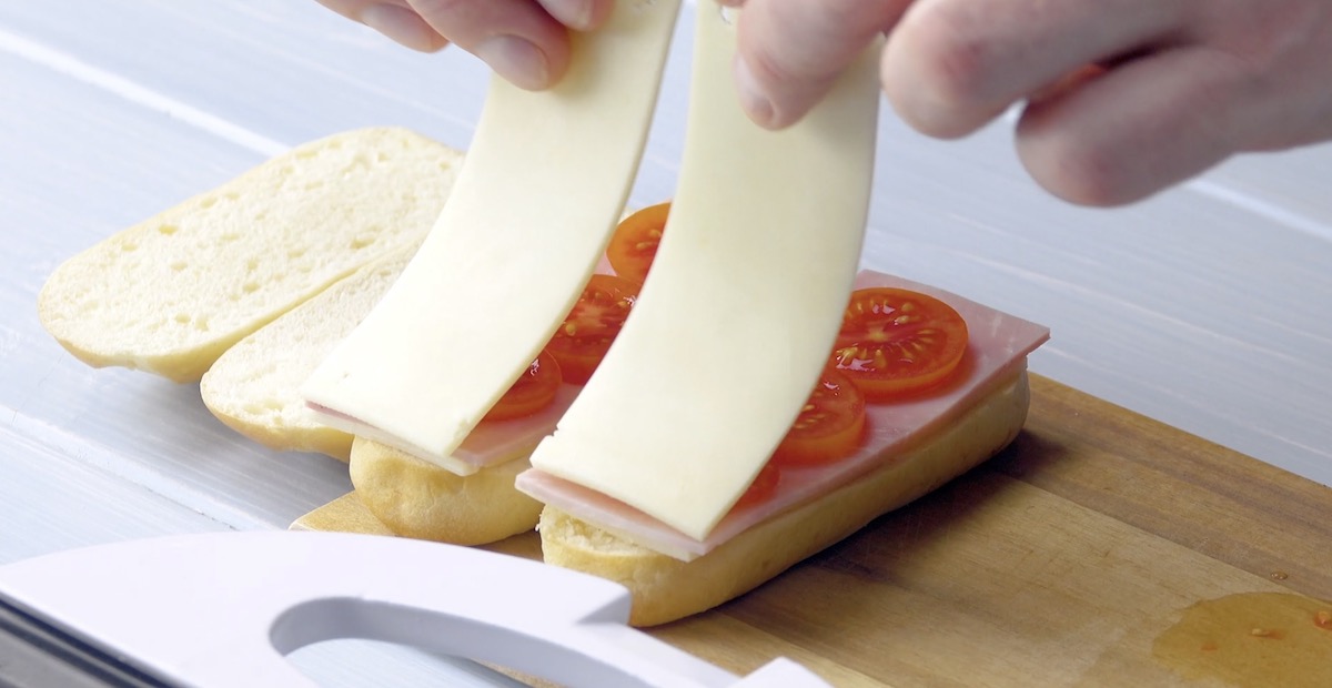 Milchbrötchen werden mit Tomatenscheiben und einer weiteren Scheibe Käse belegt.