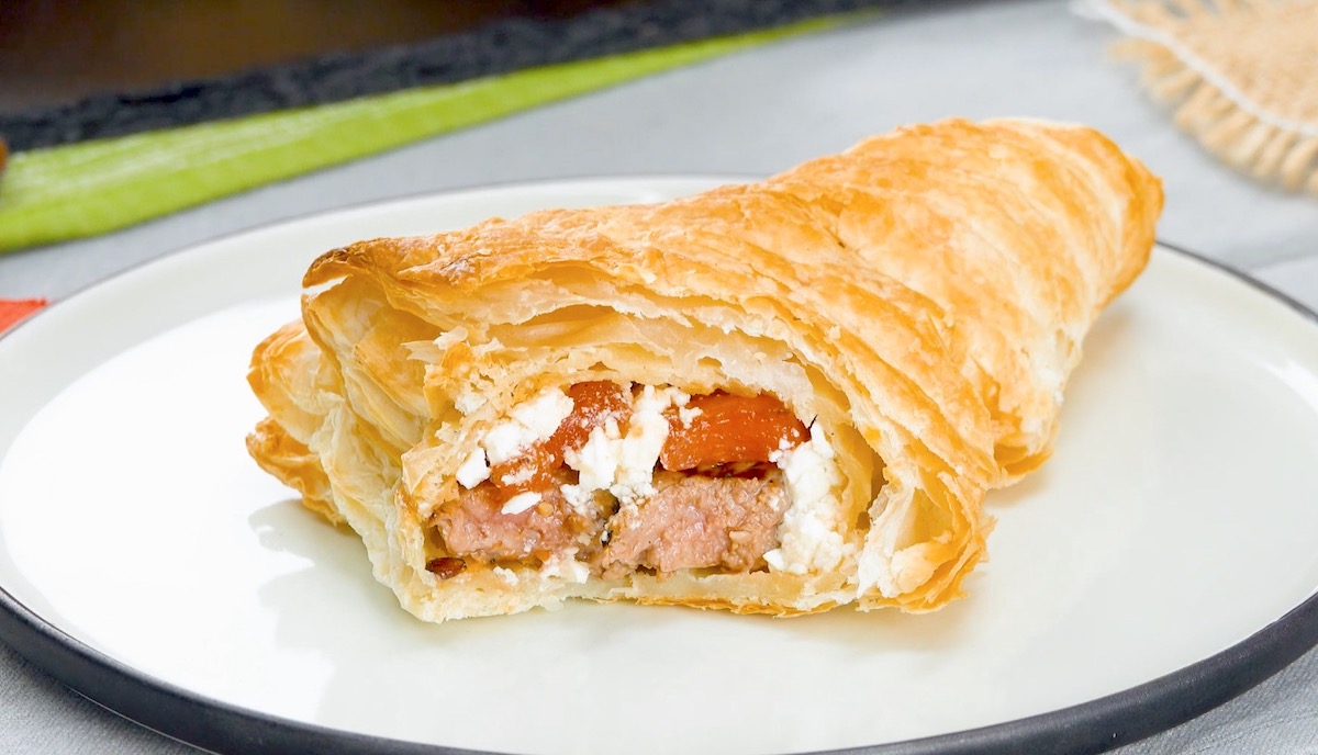 Mit Rumpsteak, Feta und Wassermelone gefüllte Blätterteigtasche, von der abgebissen wurde