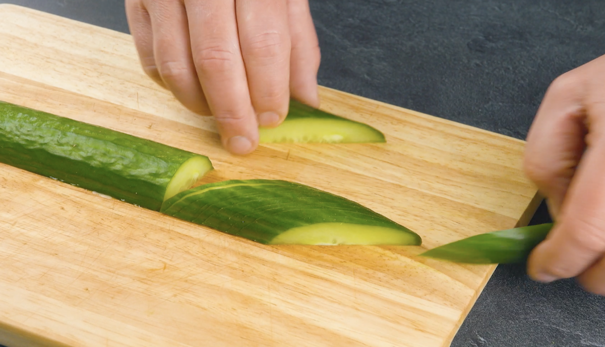 Gurke wird längs halbiert und das eine Ende in schräge, dünne Scheiben geschnitten