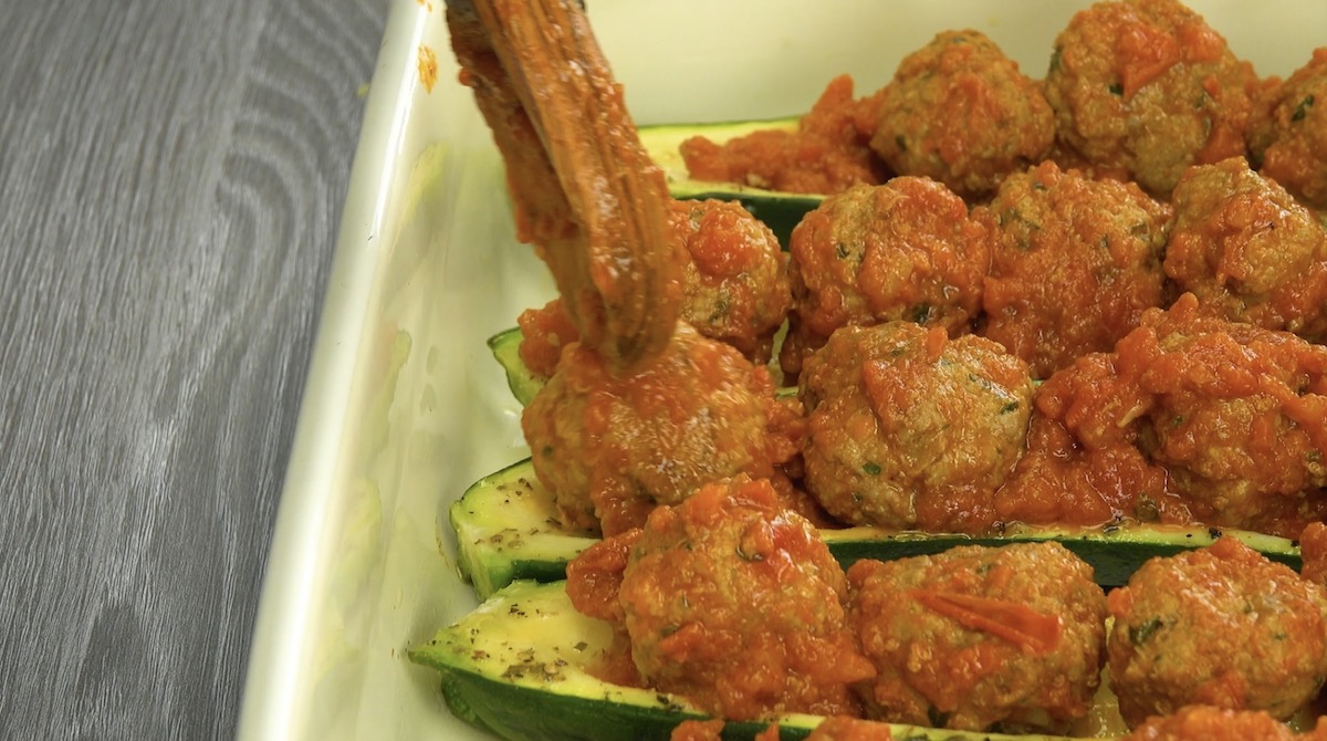Hackbällchen werden in ausgehöhlte Zucchini gelegt