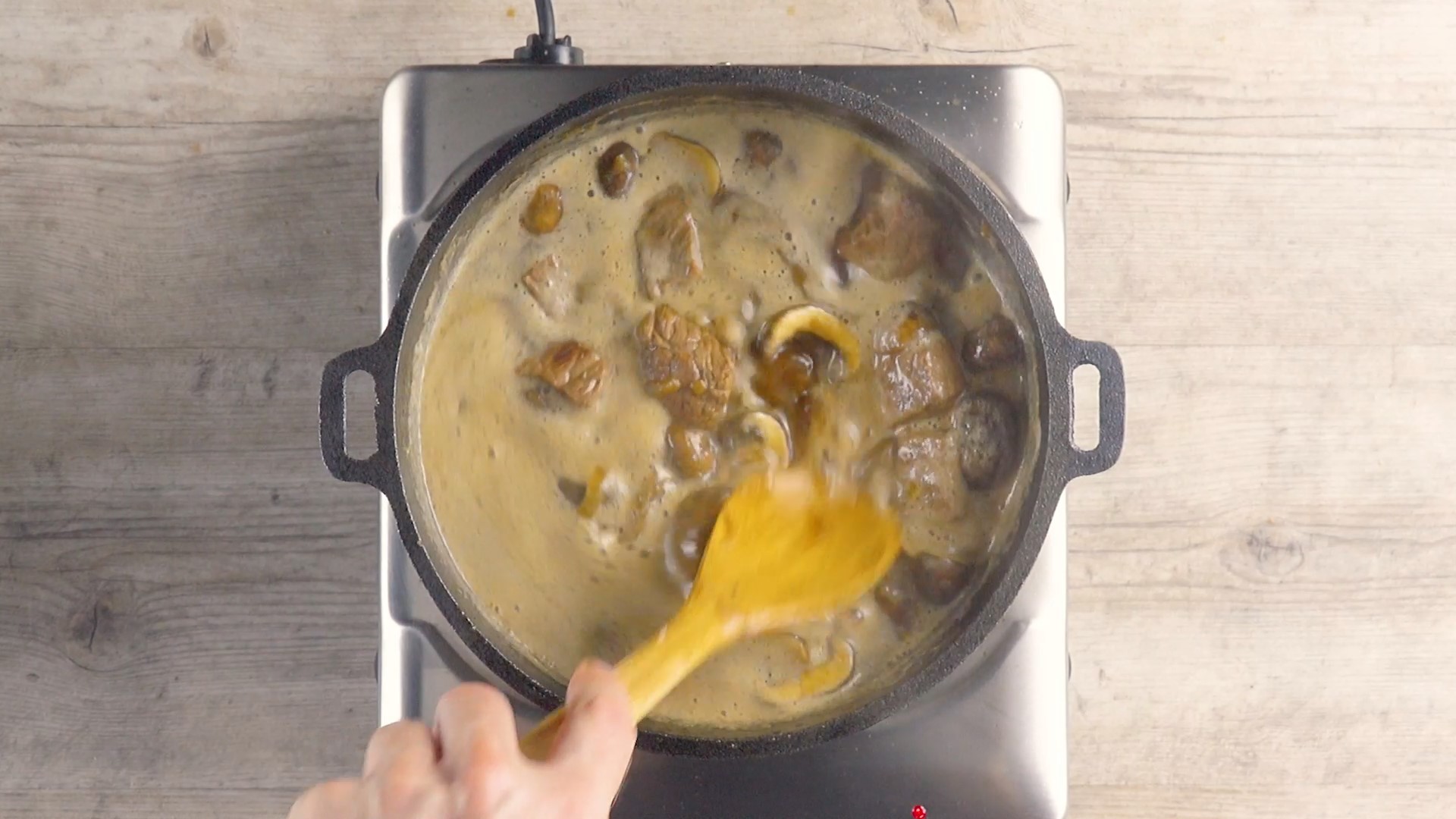 Fleisch in Bräter wird mit Bier und Rinderfond übergossen