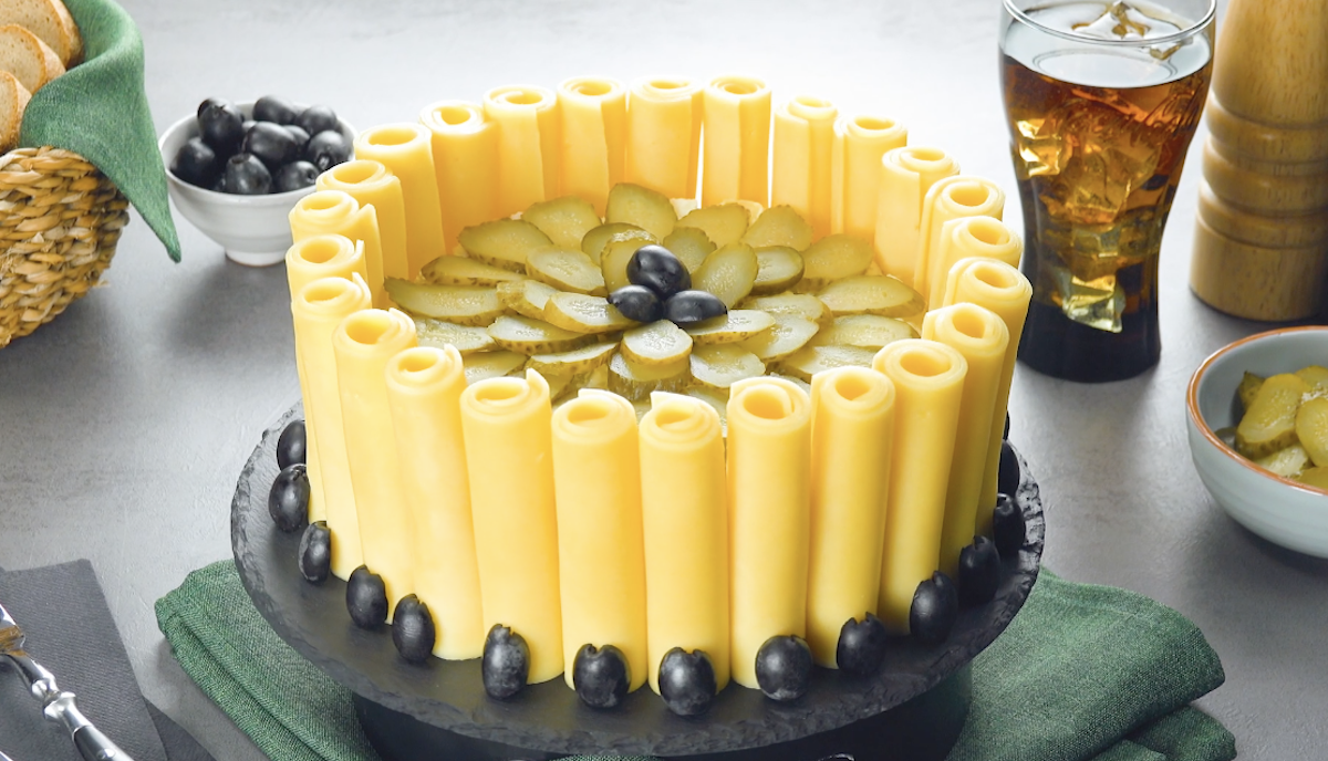 Kartoffelsalat in Kuchenform mit Käseröllchen, dekoriert mit schwarzen Oliven