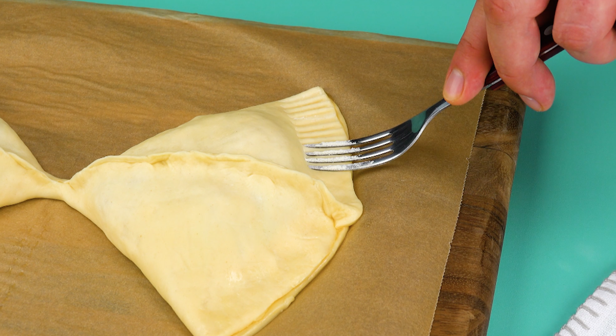 Der hintere Teil der Teigtaschen wird mit einer Gabel eingedrückt.