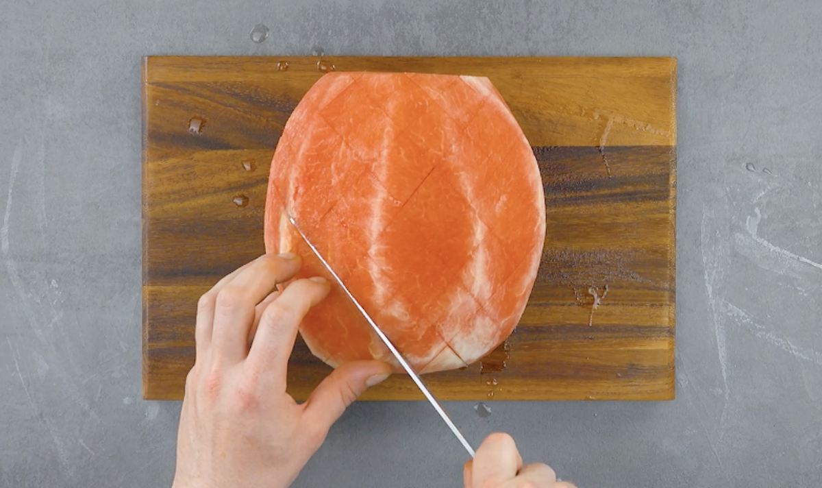 Ganze, geschälte Melone wird rautenförmig eingeschnitten