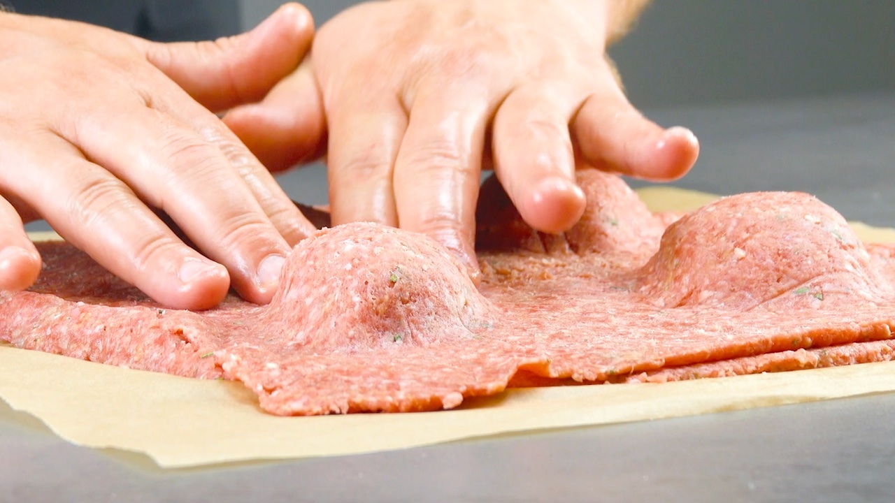 Hackfleisch wird um Käsefüllung mit Händen festgedrückt
