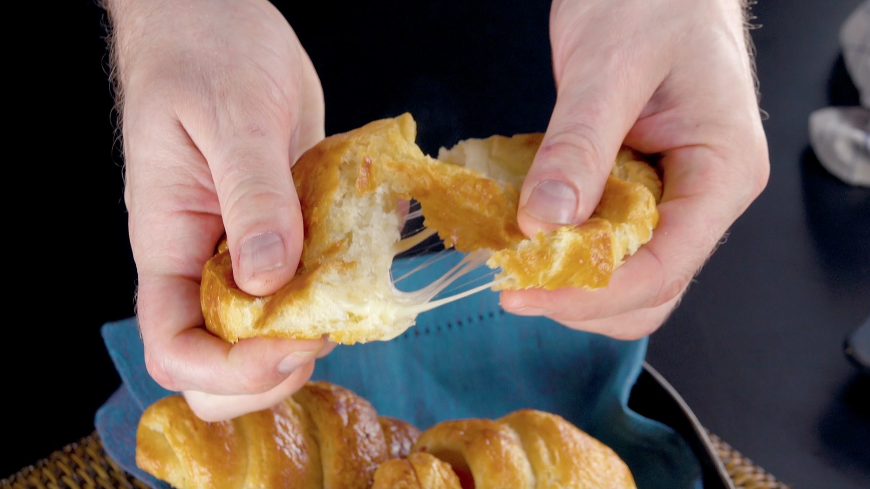 Selbstgemachtes Käse-Schinken-Croissant wird mit Fingern auseinander gezogen
