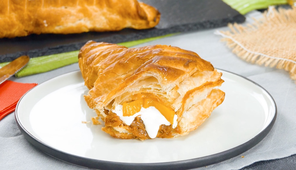 Mit Ananas, Pulled Pork und Provolone gefüllte Blätterteigtasche, von der abgebissen wurde