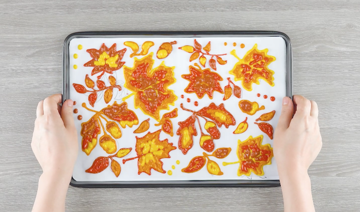 Bunte Blätter werden auf einem Backblech mit Backpapier aus Teig gezeichnet