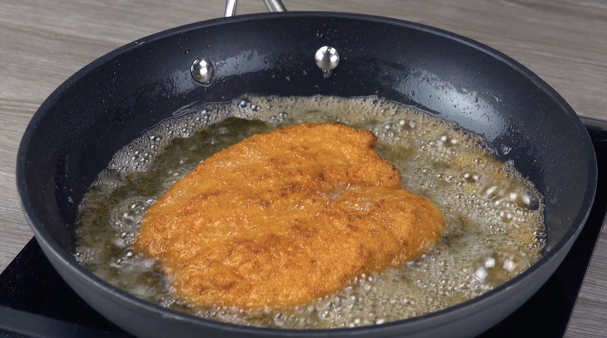 Panierte Hähnchenschnitzel werden angebraten