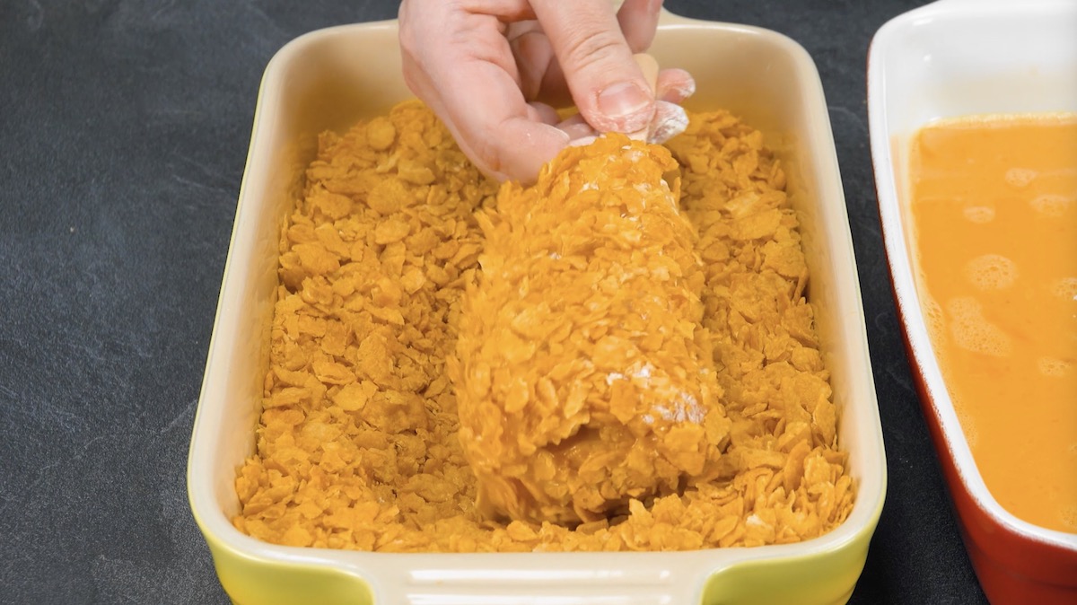 Hähnchen-Cordon-bleus am Stiel werden in Mehl, Ei und zerbröselten Conrflakes paniert