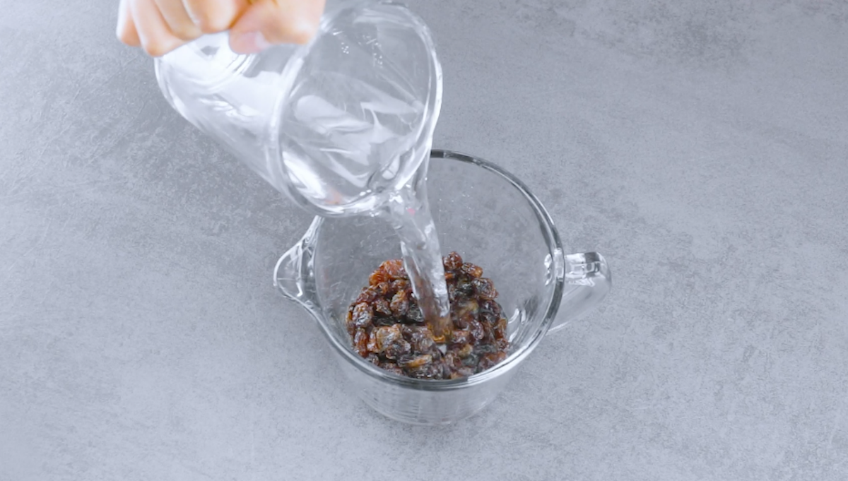 Rosinen in Messbecher werden mit Wasser übergossen