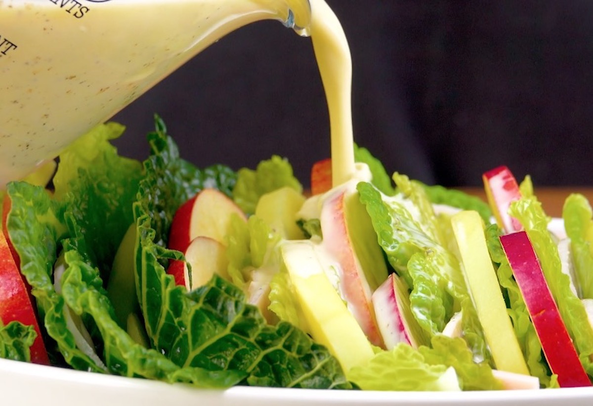 Sahne wird über einen Kartoffelauflauf mit Wirsing gegeben