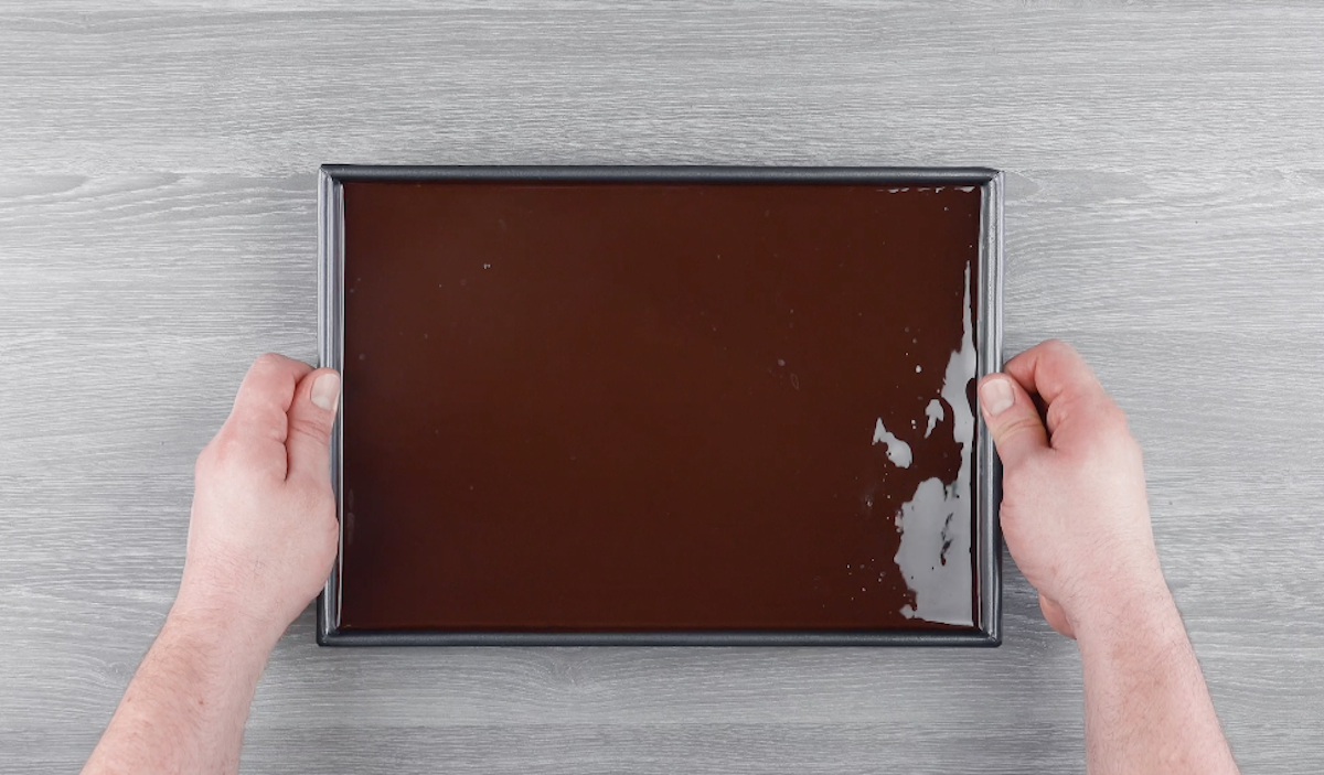 Schokoglasur wird in Backform gefüllt und gleichmäßig verteilt