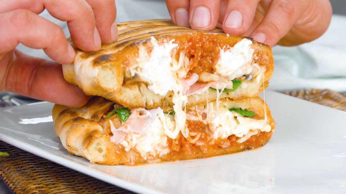 Aufgeschnittene, gegrillte Calzone mit Salsiccia und Burrata